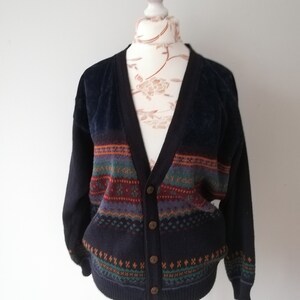 May include: A dark blue cardigan with a multi-colored patterned design. The cardigan has a V-neck and button closure.