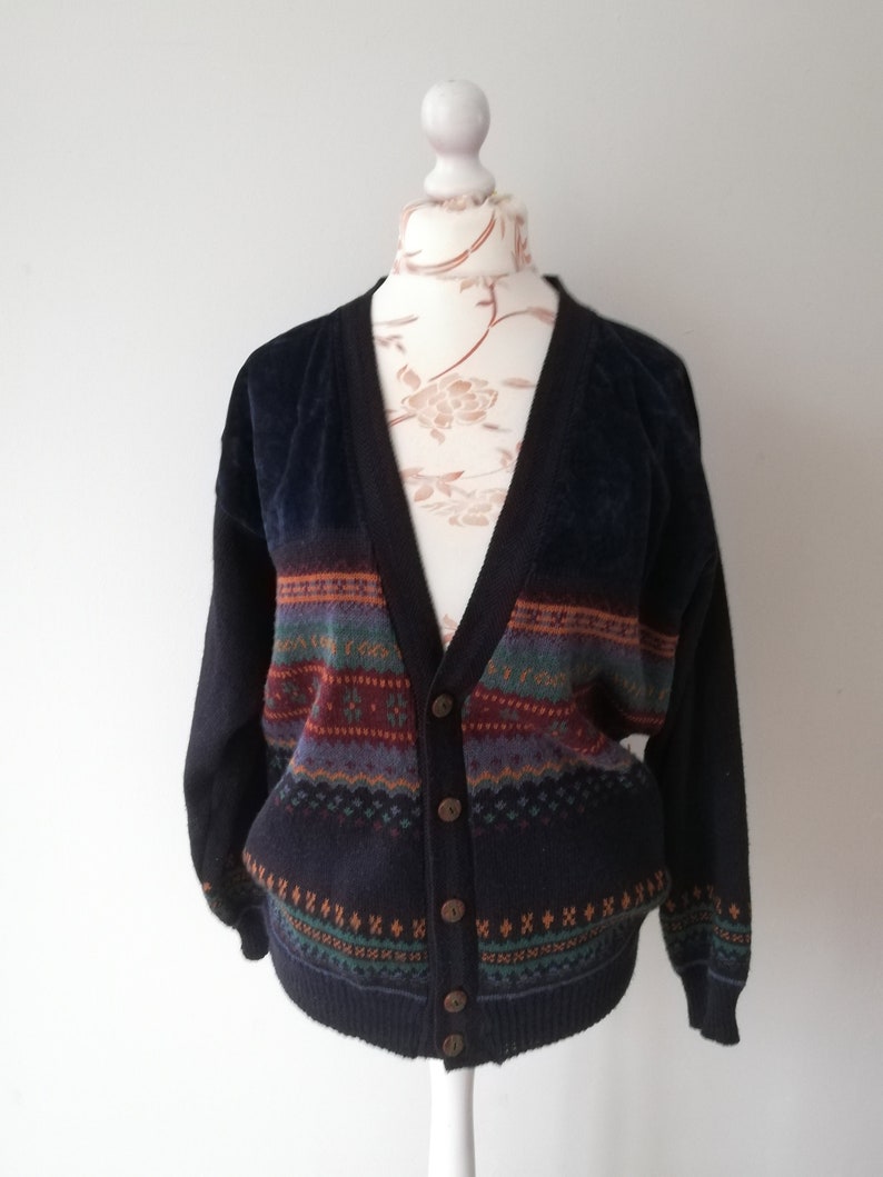May include: A dark blue cardigan with a multi-colored patterned design. The cardigan has a V-neck and button closure.