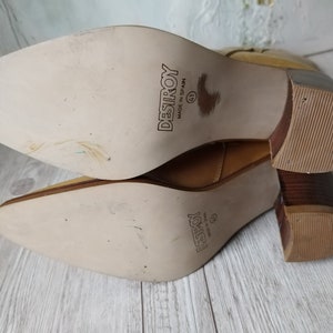 K&ouml;nnte beinhalten: Hellbraune Lederstiefel mit spitzer Zehenpartie und Blockabsatz. Die Sohlen sind hellbeige mit dem Wort "DESTROY" und der Gr&ouml;&szlig;e "41" bedruckt. Hergestellt in Spanien.