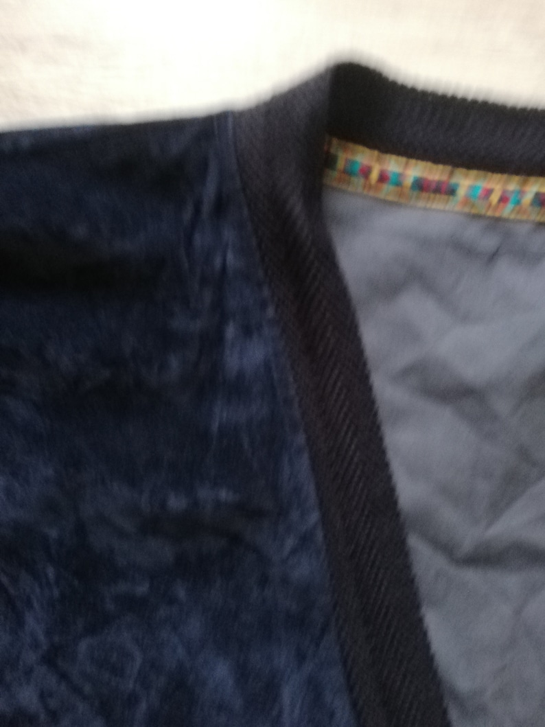 May include: A dark blue corduroy jacket with a colorful trim around the neckline.