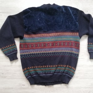 May include: A navy blue sweater with a colorful geometric pattern and a velvet panel on the back.