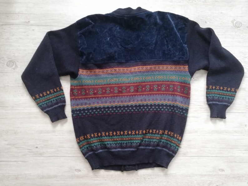 May include: A navy blue sweater with a colorful geometric pattern and a velvet panel on the back.