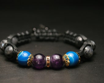 May include: A black braided bracelet with blue agate and amethyst beads. The beads are separated by gold-toned spacers.
