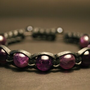May include: A black leather bracelet with purple amethyst beads.