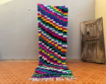 May include: A colourful, hand-woven rug with a unique, textured design. The rug is made from recycled materials and features a variety of bright colours, including pink, purple, green, yellow, and black.