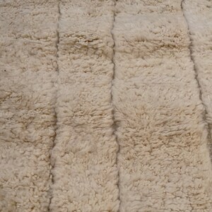 May include: A close-up of a white, fluffy rug with a textured, woven pattern. The rug has a soft, plush feel and is made of natural fibres.