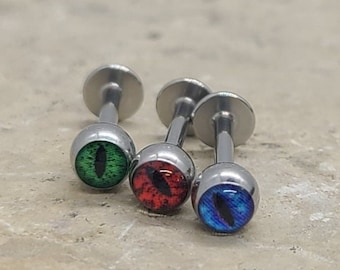 May include: Three silver barbell earrings with eye-shaped charms. The charms are green, red and blue.
