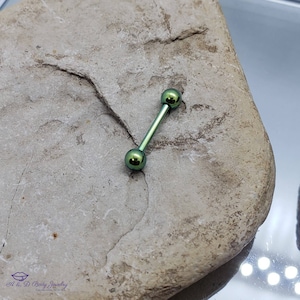 May include: A green titanium barbell with two round balls on each end. The barbell is lying on a gray rock.