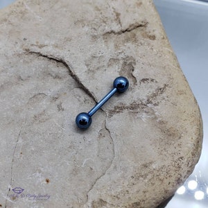 May include: A blue titanium barbell with two round balls on each end. The barbell is lying on a gray rock.