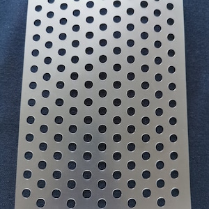 May include: A silver-coloured stencil with a grid of circular perforations. The stencil is rectangular with rounded corners. The number "1892" is printed on a black label at the bottom.