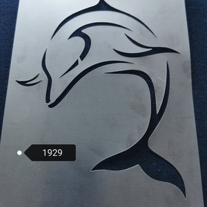 May include: A clear plastic stencil featuring a black silhouette of a stylised dolphin leaping from the water. The stencil has a white circle with the number 1929 printed on it.