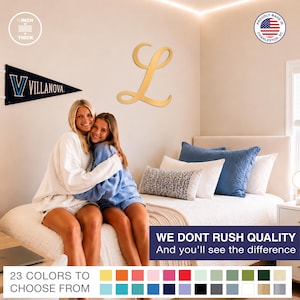 May include: A gold-colored, cursive letter L wall decoration that is 1/2 inch thick. The wall art is displayed above a bed. The image includes text stating, Proudly made in Charleston, SC, and We dont rush quality. And you'll see the difference.