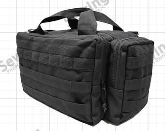 May include: A black tactical utility bag featuring multiple external webbing straps for modular attachments, a top carry handle, and a side zippered compartment. The rectangular bag is constructed from durable fabric with heavy-duty zippers.
