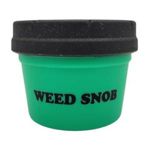 Può includere: Un contenitore verde con coperchio nero. Le parole "WEED SNOB" sono stampate in nero sulla parte anteriore del contenitore. Il contenitore è cilindrico con una parte superiore leggermente svasata.