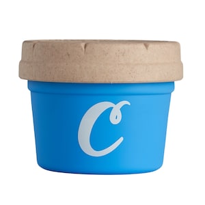 Könnte beinhalten: Ein kleiner, runder Behälter in Blau mit einem braunen Deckel. Der Behälter hat einen weißen Buchstaben "C" auf der Vorderseite.