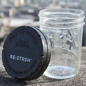 May include: A black lid with the text "RE:STASH™ Made with renewable fibres" and a clear glass jar with a wide mouth.