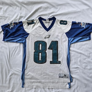 May include: A white and blue mesh jersey featuring the number 81 in teal with black outlines on the front and shoulders. The Philadelphia Eagles logo is centred below the V-neck collar. The sleeves display a Super Bowl XXXIX patch.