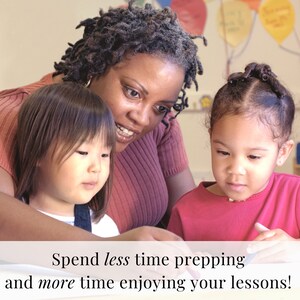 May include: A teacher works with two young students in a classroom setting. The teacher is wearing a pink shirt and the students are wearing pink shirts. The students are sitting at a table and appear to be working on a project.