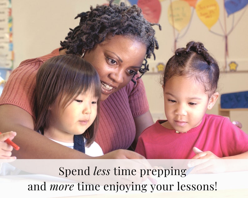May include: A teacher works with two young students in a classroom setting. The teacher is wearing a pink shirt and the students are wearing pink shirts. The students are sitting at a table and appear to be working on a project.