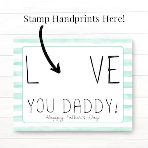 May include: A white card with blue and white stripes on the border. The card says "I LOVE YOU DADDY! Happy Father's Day" with an arrow pointing to a blank space that says "Stamp Handprints Here!"