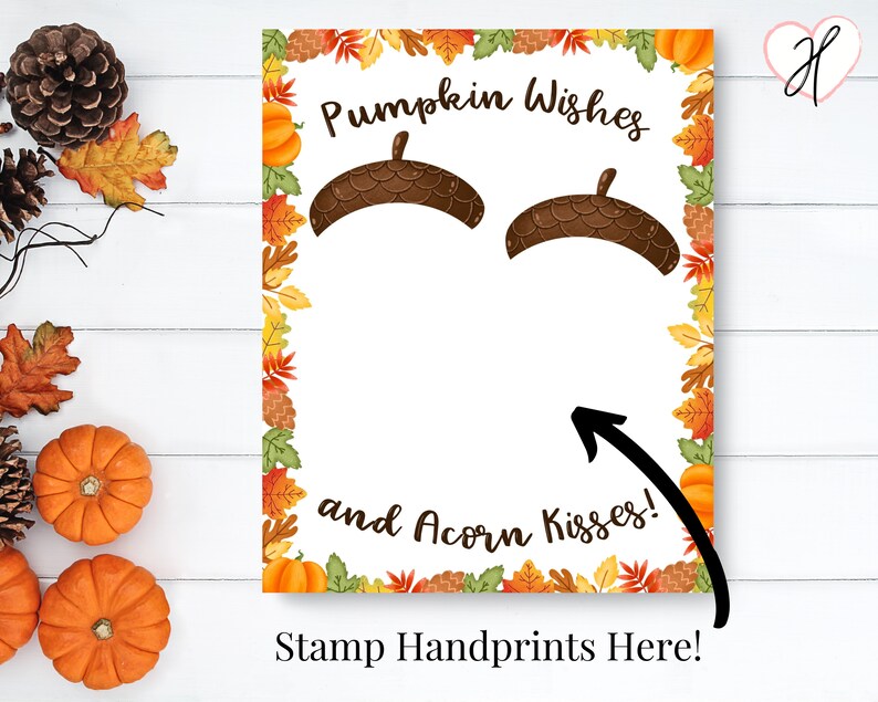 May include: A printable fall-themed baby shower game with the text "Pumpkin Wishes and Acorn Kisses!" and "Stamp Handprints Here!"  The game features a white background with a border of fall leaves and pumpkins. There are two acorn shapes at the top of the page for handprints.