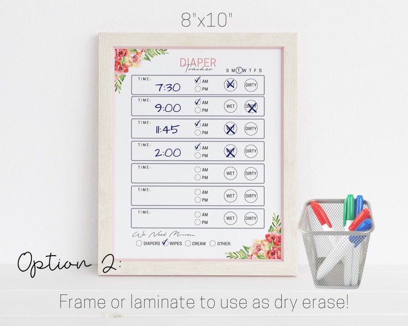 May include: A white 8x10 inch dry erase board with a floral border. The board is titled "Diaper Tracker" and has a checklist for tracking diaper changes, including time, AM/PM, wet, and dirty. The board is framed in a light wood frame.