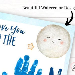 Beautiful closeup of the watercolor details on the I love you to the moon print. A smiling moon in the top right corner, light blue border with cute stars and hearts that surround the page. Handprints are stamped in place of the letter O in moon.