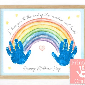 Peut inclure: Une impression encadrée avec un arc-en-ciel à l'aquarelle, des empreintes de mains bleues et le texte "I love you to the end of the rainbow and back!" et "Happy Mother's Day." Comprend un cœur et des étoiles.
