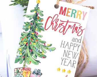 May include: A white gift tag with a watercolor Christmas tree design. The tag reads "Merry Christmas and Happy New Year" in colorful lettering. Presents are at the base of the tree. The tag is tied with twine and has a sprig of greenery.