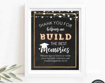 Puede incluir: Un letrero de graduación enmarcado con el texto "THANK YOU FOR helping me BUILD THE BEST Memories." El letrero es negro con detalles dorados y un marco blanco. El letrero también incluye el texto "Please sign a block or write your favorite memory we made together on it!"