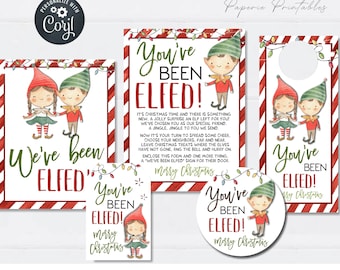Op de afbeelding: Printbare kerst-elfen deurhanger met rode en witte strepen, een rood en wit gestreept deurschild, een ronde sticker en een vierkant schild. De borden en de sticker hebben allemaal de tekst "You've Been Elfed!" met een kerst-elfenillustratie. De deurhanger heeft een uitsparing om op te hangen.