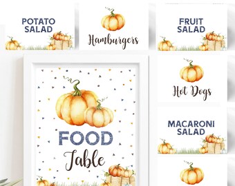 Op de afbeelding: Printbare voedseletiketten met een aquarel-pompoenontwerp op een achtergrond van blauwe en oranje confetti. De etiketten zeggen "Aardappelsalade", "Hamburgers", "Fruitsalade", "Hotdogs", "Macaronisalade" en "Groenten".