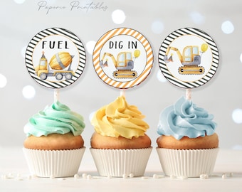 May include: Three cupcakes with yellow, blue, and green frosting topped with construction-themed cupcake toppers. The toppers feature a yellow cement mixer with the word "FUEL", a yellow excavator with the words "DIG IN", and a yellow excavator with black and gold accents.