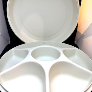 May include: Two-piece off-white serving set. The top piece is a large, round platter. The bottom piece is a divided serving tray with five compartments. The set is made of a durable, lightweight material.