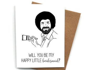 May include: A white card with a black and white illustration of a man with a paintbrush. The text on the card reads "Will you be my happy little bridesmaid?"