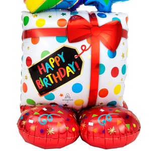 May include: A large, colorful balloon shaped like a gift box with a cupcake on top. The gift box has a red bow and a tag that says "Happy Birthday!" The cupcake has a rainbow swirl and sprinkles. There are three stars on top of the cupcake, one red, one blue, and one turquoise.