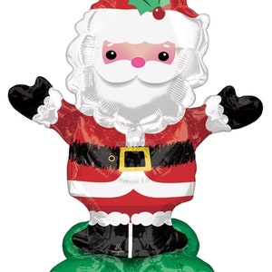 May include: A red and white Santa Claus balloon with a green holly sprig on his hat. He is wearing a black belt and has a white beard. He is standing on a green balloon shaped like a pair of feet.