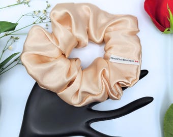 May include: A light peach-colored satin scrunchie with a white label that reads "Sims Chic Boutique".