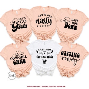 K&ouml;nnte beinhalten: F&uuml;nf T-Shirts in Pfirsich und Wei&szlig; mit schwarzem Text und Grafiken. Die Shirts zeigen S&auml;tze wie "Let's Go Girls", "Let's Get Nasty", "Last Hoe Down", "Cowgirl Gang", "Last Ride for the Bride" und "Getting Rowdy".
