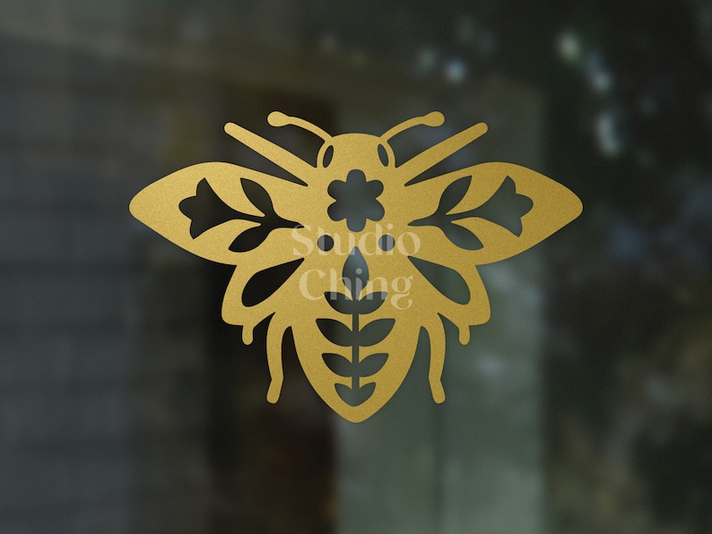 May include: A gold-coloured bee design with detailed floral cutouts on the wings and body. The text "Studio Ching" is visible. The bee is a decorative element, possibly for crafts or home decor.