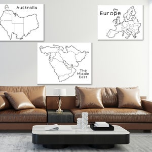 May include: Three black and white outline maps of Australia, Europe, and the Middle East are displayed on a white wall above a brown leather couch.