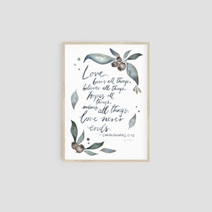 Könnte beinhalten: Ein Aquarelldruck mit einem Zitat aus der Bibel, 1 Korinther 13,7-8: "Die Liebe erträgt alles, glaubt alles, hofft alles, erduldet alles. Die Liebe hört niemals auf." Das Zitat ist von Aquarellblättern und Beeren umgeben.