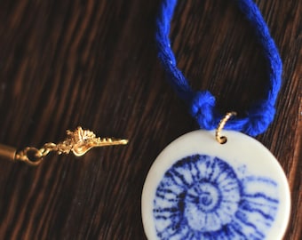 Collier en porcelaine planispirale et illustration avec breloques coquillage