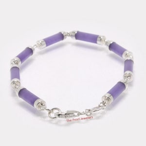 May include: A bracelet featuring cylindrical lavender beads connected by silver-toned metal links. The bracelet has a secure clasp and is displayed on a white surface. The text "The Pearl Jewelers" is visible on the clasp.