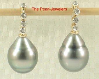 Könnte beinhalten: Ein Paar graue Perlenohrringe mit goldenen Akzenten und kleinen Diamanten. Die Ohrringe haben eine Tropfenform und sind an einem goldenen Pfosten mit drei kleinen Diamanten befestigt. Der Text "The Pearl Jewelers" ist sichtbar.