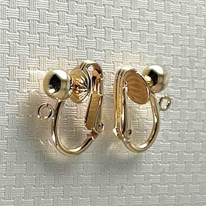 May include: A pair of gold-tone clip-on earrings with a round ball at the end of each earring.