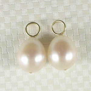 Op de afbeelding: Twee witte parel oorbellen met gouden oorhaken.