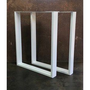 May include: Two white metal table legs with a square frame design. The legs are made of sturdy metal and have a clean, modern look.