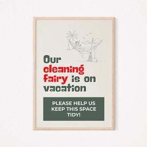 May include: A framed print with a light beige background and a wooden frame. The print features the text "Our cleaning fairy is on vacation" in a mix of green and red fonts, along with a black and white illustration of a person in a hammock. Below the text is a dark green rectangle with the text "PLEASE HELP US KEEP THIS SPACE TIDY!"