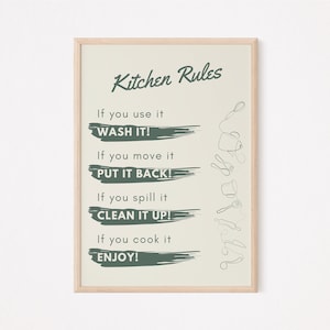May include: A framed print with a green background and white text that reads "Kitchen Rules". The rules are: "If you use it WASH IT!", "If you move it PUT IT BACK!", "If you spill it CLEAN IT UP!", and "If you cook it ENJOY!"